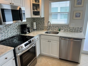 A modern kitchen with a built-in oven, a microwave, a coffee maker, and a dishwasher. - Casa Blanca - Villa C12 (Sarasota)