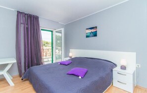 Ein Schlafzimmer mit Bett, Schreibtisch und Balkon.