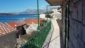 Een balkon met uitzicht op zee en bergen.