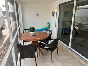 Eine Terrasse mit einem runden Holztisch, schwarzen Korbstühlen und einem Blumentopf.
