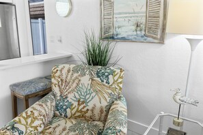 A room with a patterned armchair, a small table, a potted plant, a painting, and a lamp. - Casa Blanca Villa - VA04 (Sarasota)
