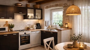 A modern kitchen with dark cabinetry, a white stove, and a dining area with a round table. - House Ivana (Krsan)