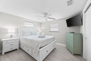 A bedroom with a bed, nightstands, a dresser, a ceiling fan, and a TV mounted on the wall. - Casa Blanca - Villa B08 (Sarasota)