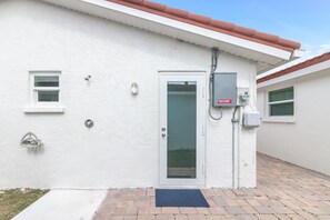 A white building with a door, a small window, and a utility box. - Casa Blanca - Villa B08 (Sarasota)