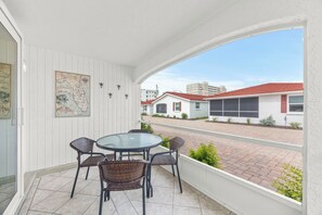 A covered outdoor area with a table and chairs, a map on the wall, and a view of buildings in the distance. - Casa Blanca - Villa B08 (Sarasota)