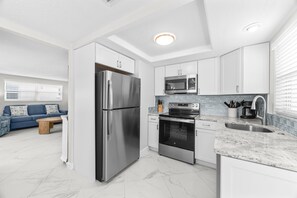 A modern kitchen with stainless steel appliances, white cabinetry, and a marble countertop. - Casa Blanca - Villa B14 (Sarasota)