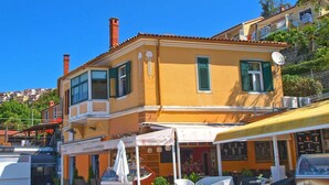Un edificio giallo con persiane verdi, posti a sedere all'aperto e una vetrina ben visibile.