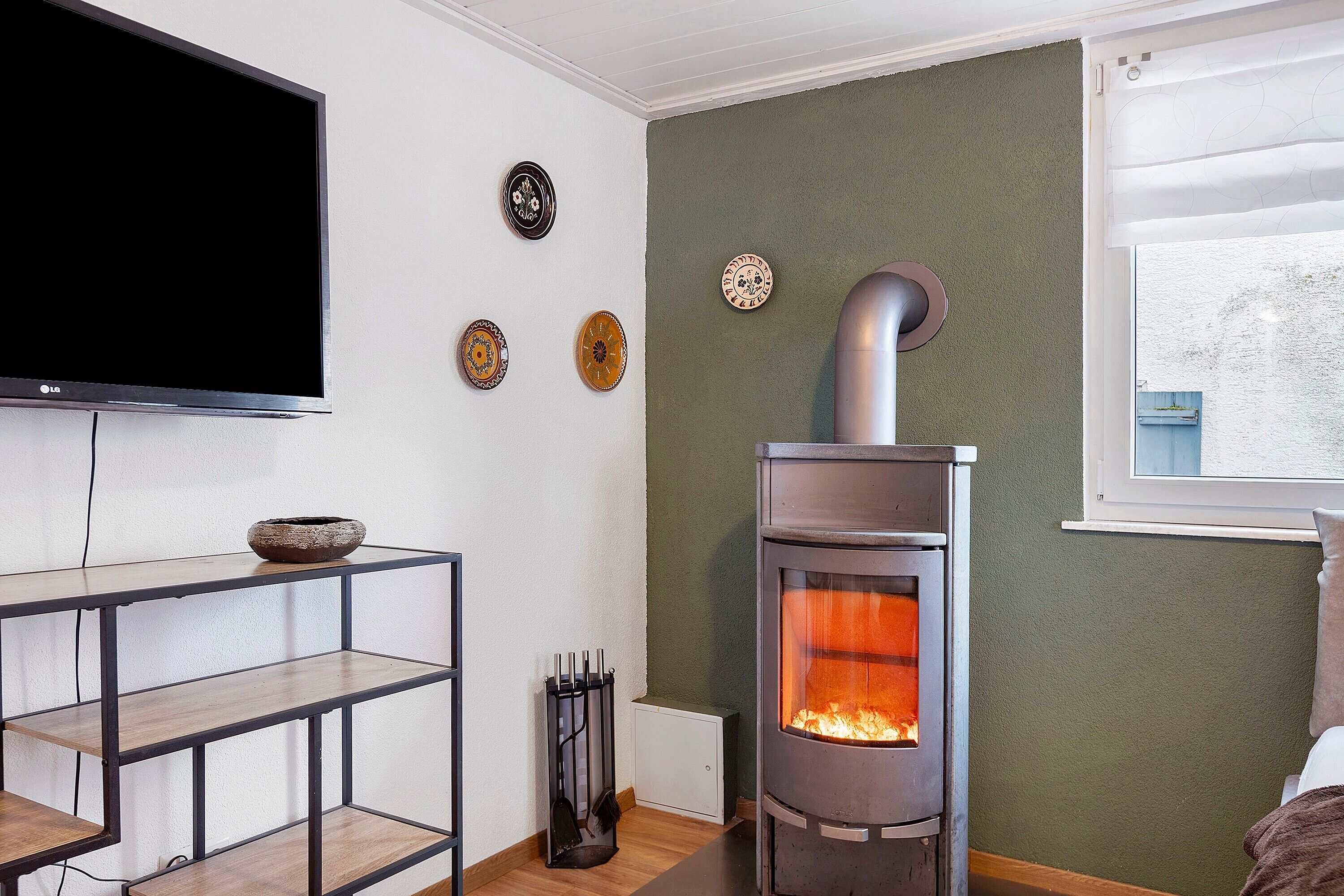 A living room with a TV, a fireplace, and decorative plates on the wall.