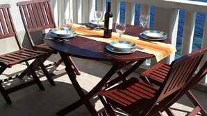 A terrace with a table set for two, overlooking a body of water. - Apartments Ruzica (Vis)