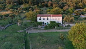 A white building with a red roof surrounded by a stone wall and greenery. - House Viskic (Rab)
