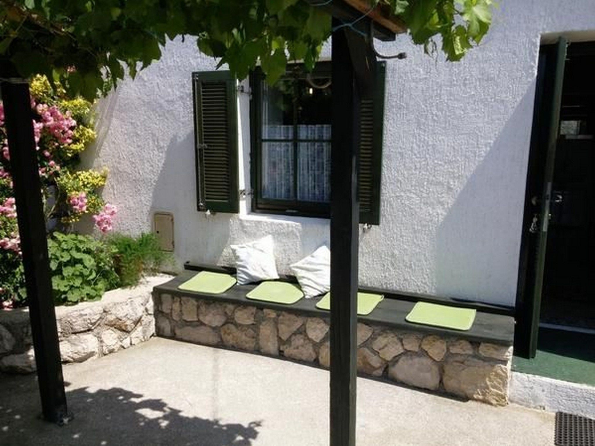 A small outdoor seating area with a stone bench and a pergola.
