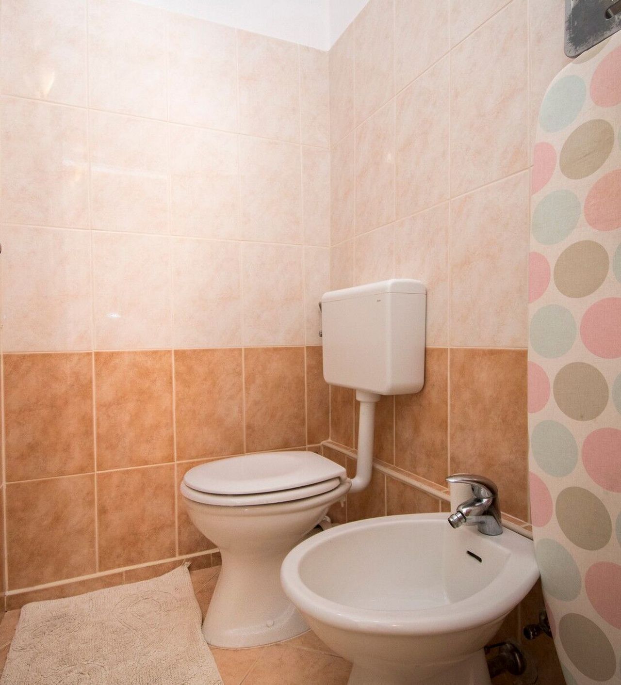 Un baño con inodoro, bidé y paredes de azulejos.