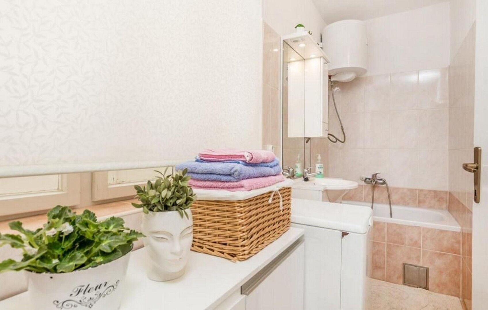 A bathroom with a white sink, a mirror, a shower, and a towel rack.