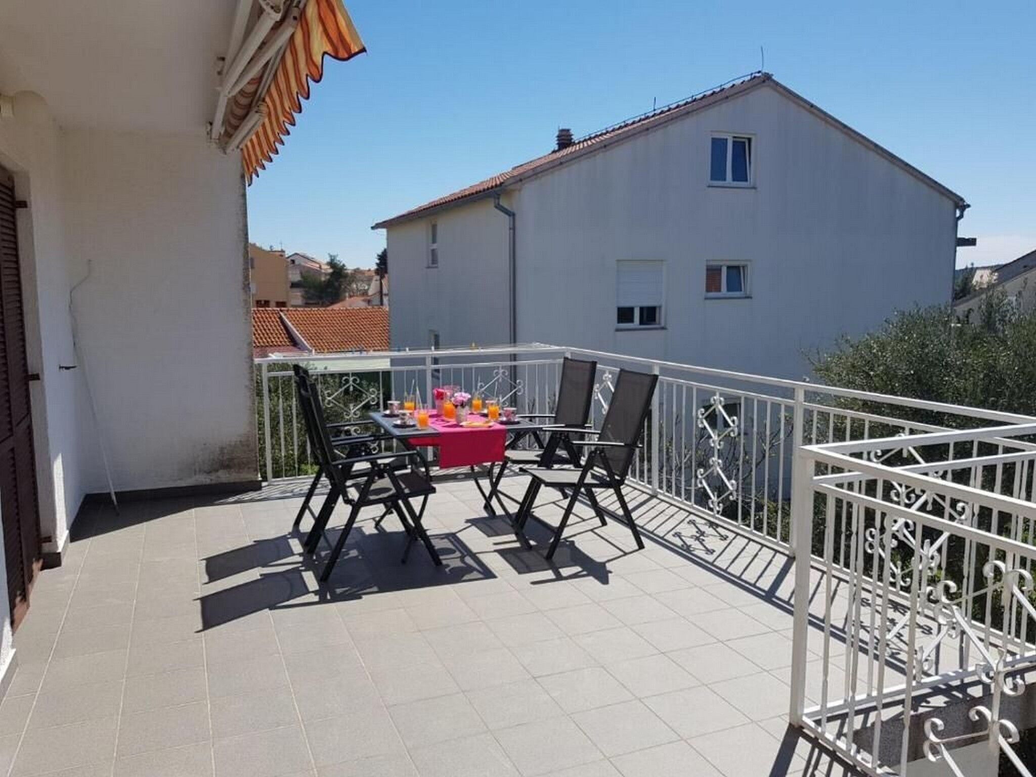 A balcony with a table set for two, a chair, and a railing.
