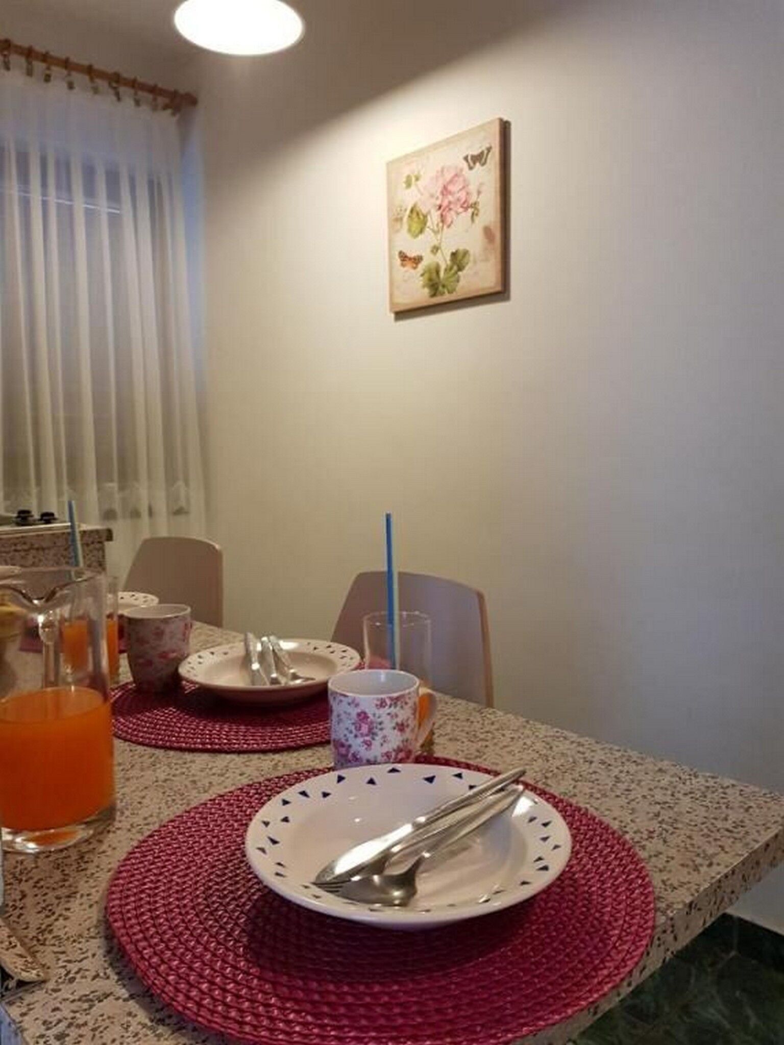 Een eettafel met borden, bestek en een karaf sinaasappelsap.