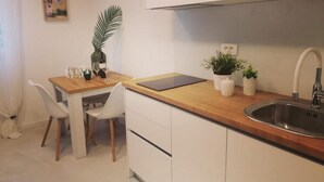 A small kitchenette with a wooden countertop, white cabinets, a sink, and a potted plant. - Apartments Diana Lovetovo (Vodice)