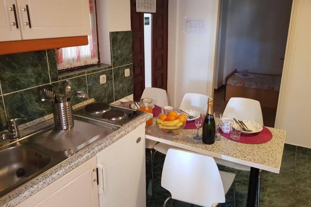 Egy kis méretű konyha mosogatóval, tűzhellyel, valamint egy étkezősarokkal, ahol két személy számára van asztal és szék.