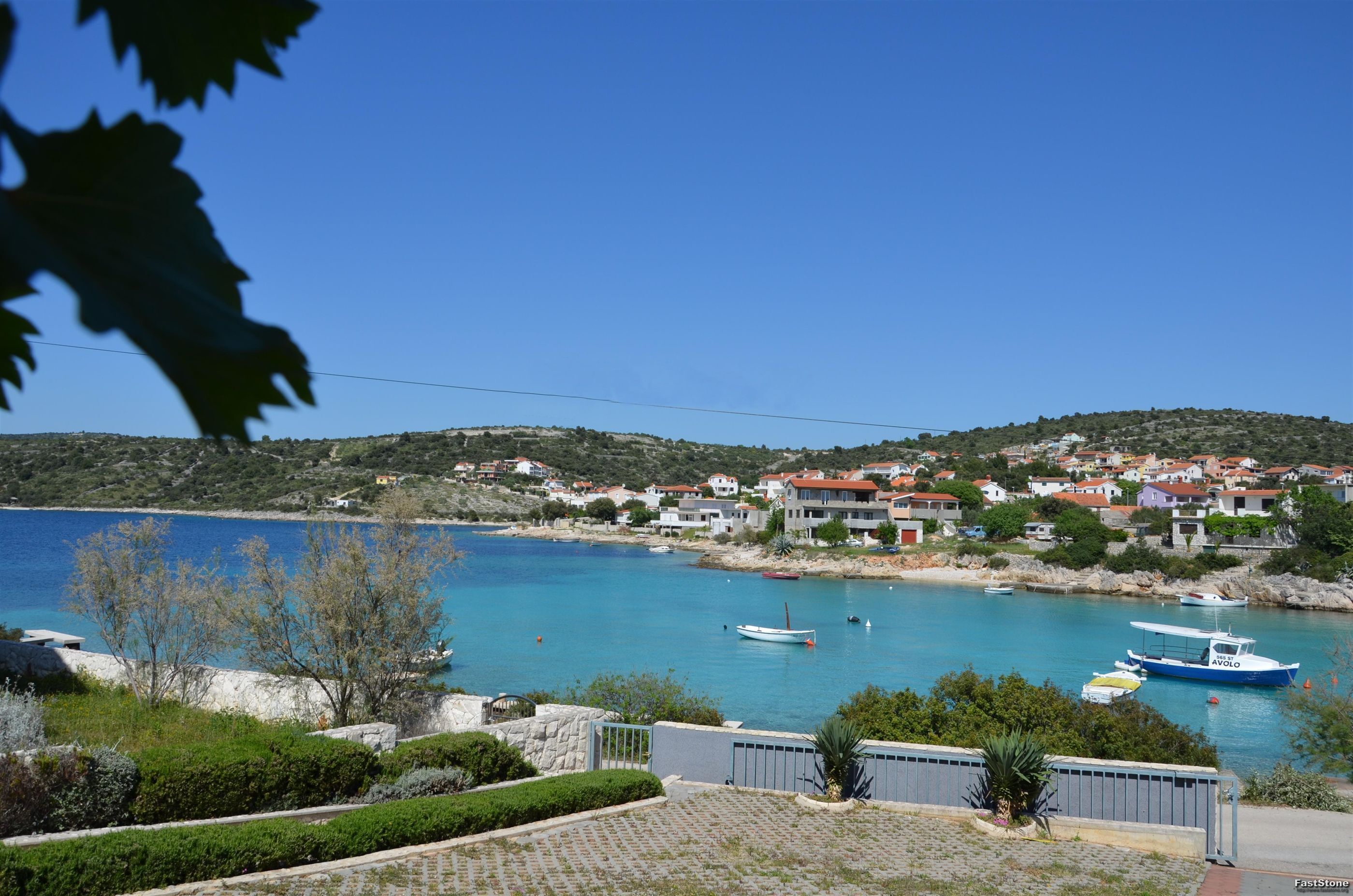 A coastal town with houses, boats, and a clear blue sky.