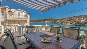 Eine Terrasse mit Tisch für zwei Personen mit Blick auf eine Küstenstadt und das Meer.