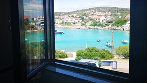 Eine Küstenstadt mit vor Anker liegenden Booten in einem Hafen, Häuser im Hintergrund und Blick durch ein Fenster.