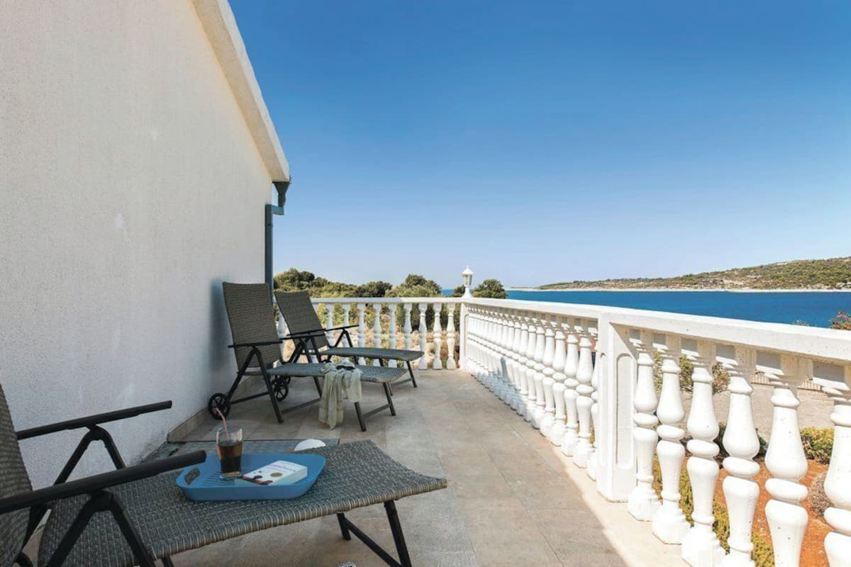 A balcony with two lounge chairs, a table with a tray, and a view of the sea.