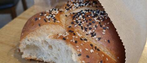 A loaf of bread with sesame seeds on a wooden cutting board.