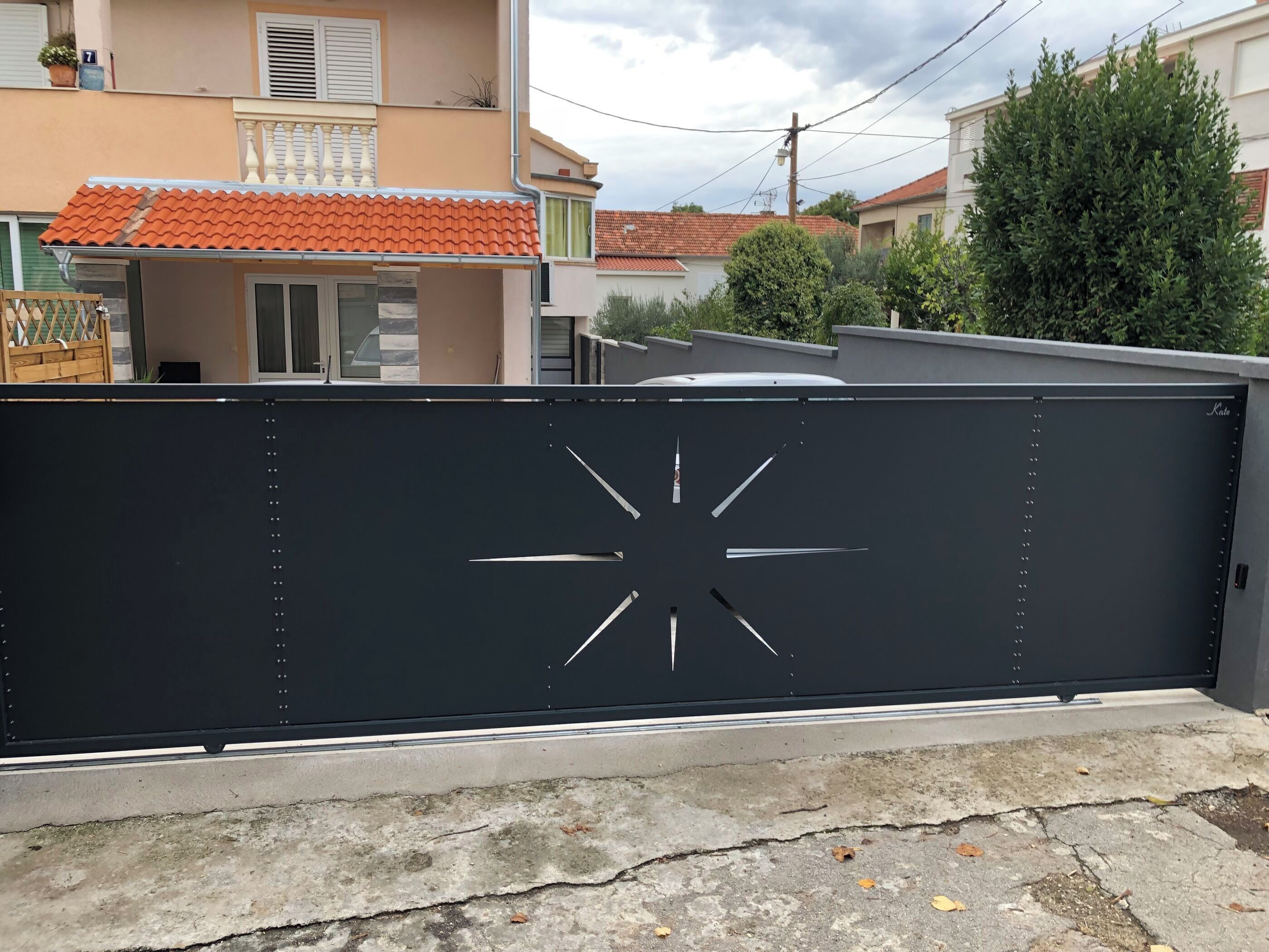 A gated entrance with a black metal gate featuring a star-like design.