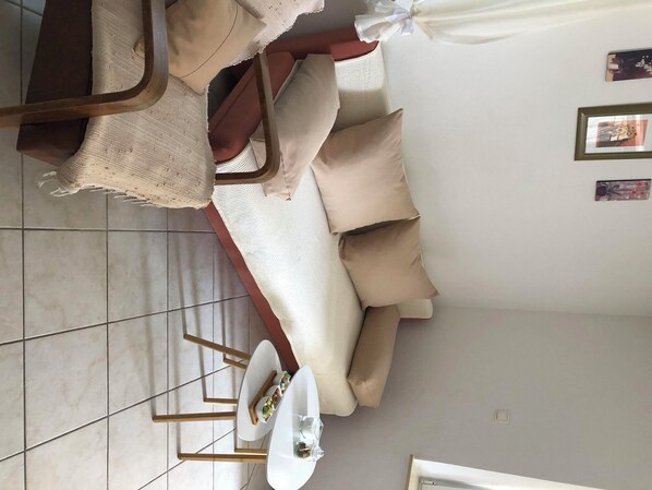Ein modernes Wohnzimmer mit einem beigefarbenen Sofa, einem weißen Couchtisch und einem kleinen Beistelltisch.