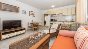 Ett kompakt bostadsutrymme med TV, matbord, stolar, en soffa och ett köksutrymme.