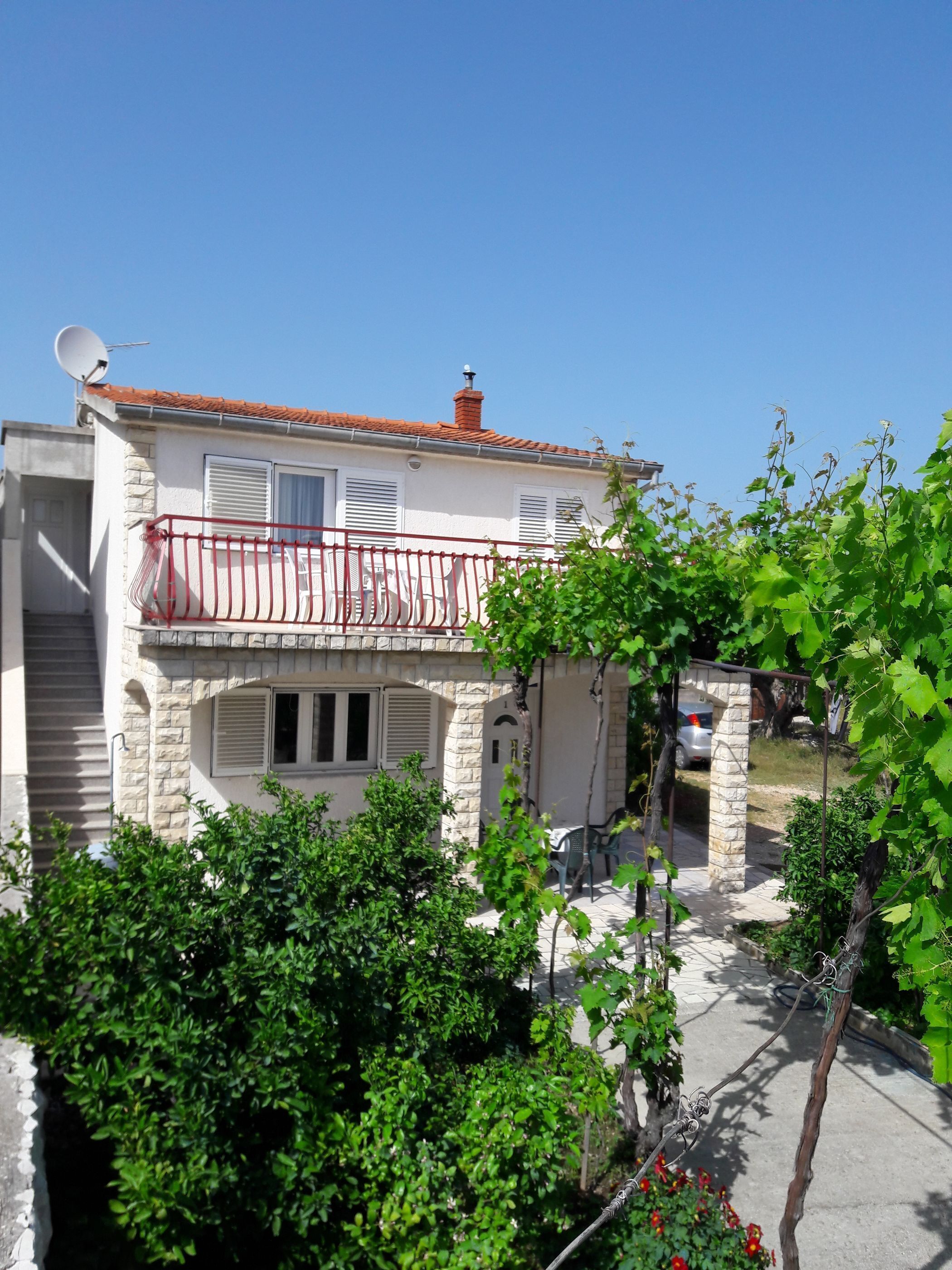 A two-story building with a balcony, stone facade, and a clear blue sky.