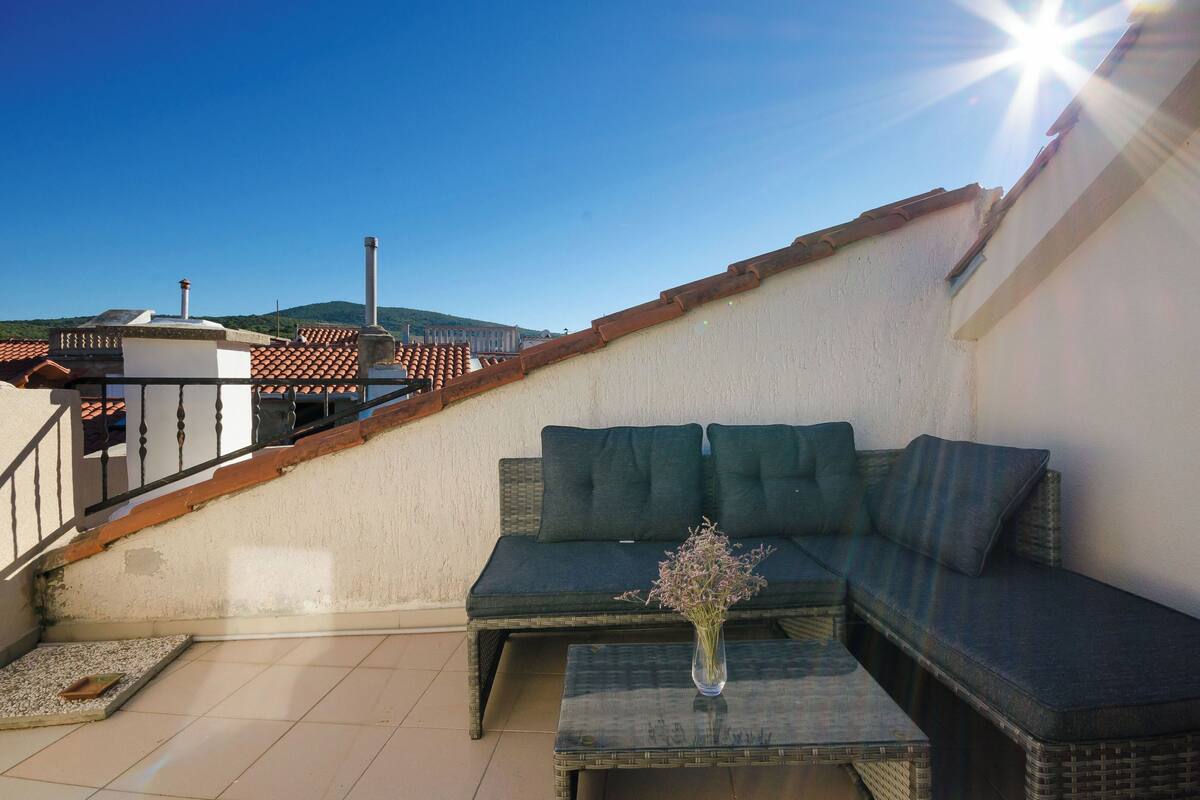 A balcony with a sofa and a table, a tiled floor, and a railing.