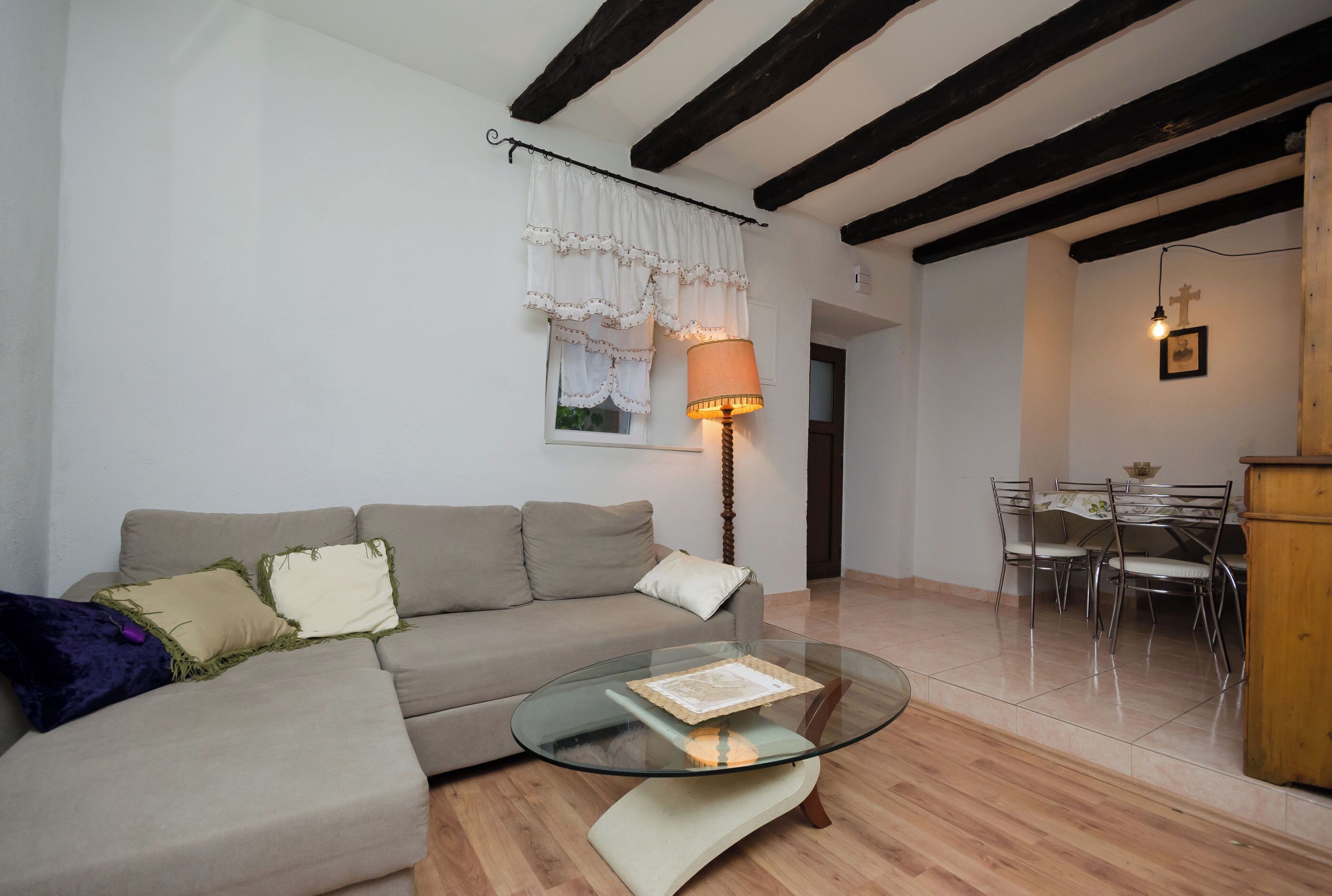 Un salon comprenant un canapé, une table basse en verre, une table à manger avec des chaises et une lampe.