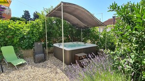 A hot tub surrounded by greenery, a green chair, and a wooden bench. - Apartment On the top (Jelsa)