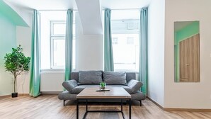 Ein modernes Wohnzimmer mit grauem Sofa, Holztisch und einer Topfpflanze.