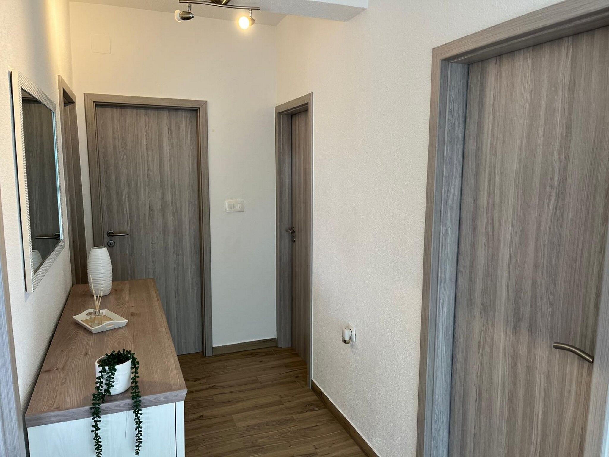 Ein Flur mit Holzboden, einer weißen Wand und zwei Holztüren.