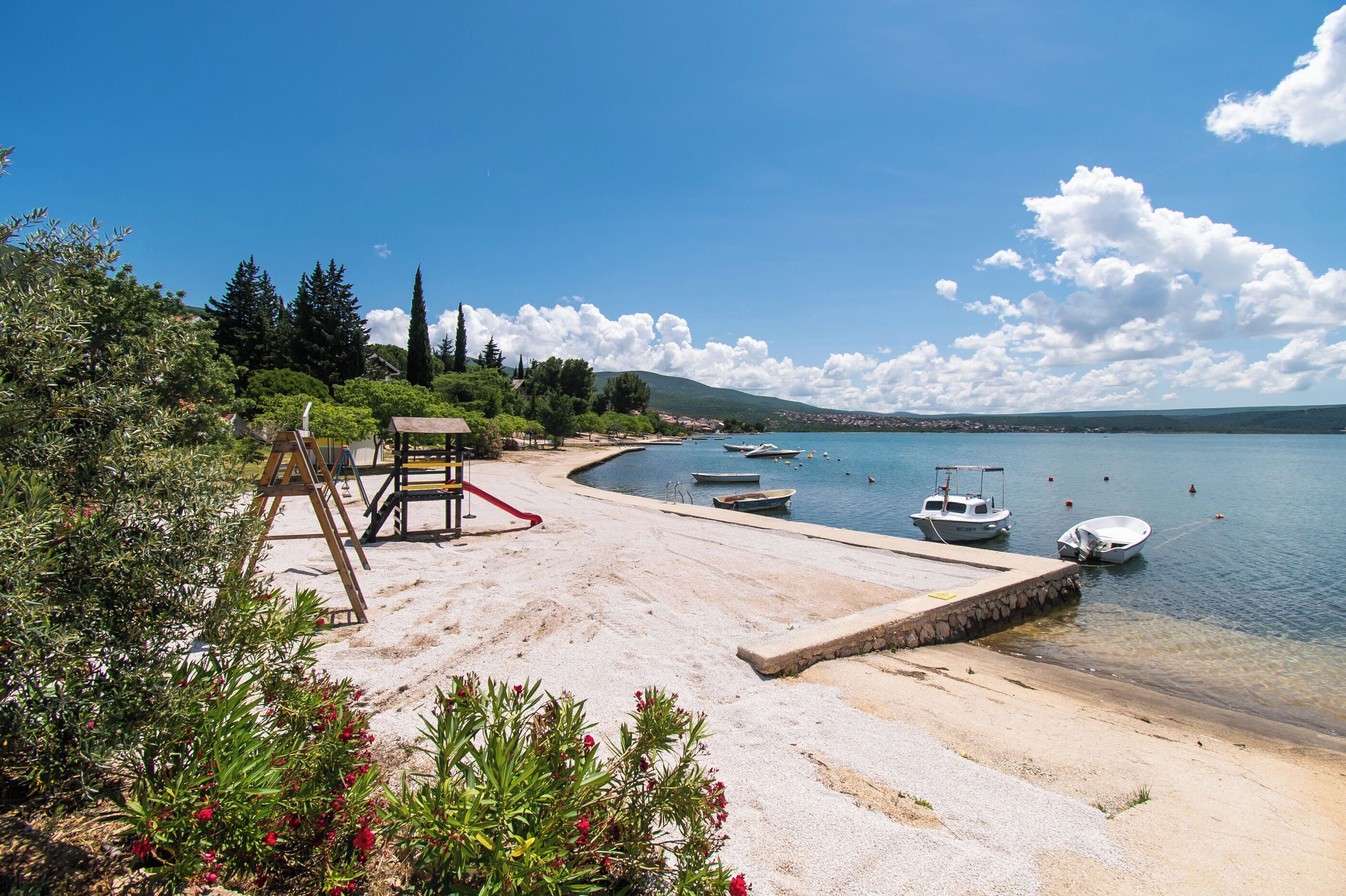 A beach with boats, a wooden structure, and clear skies.