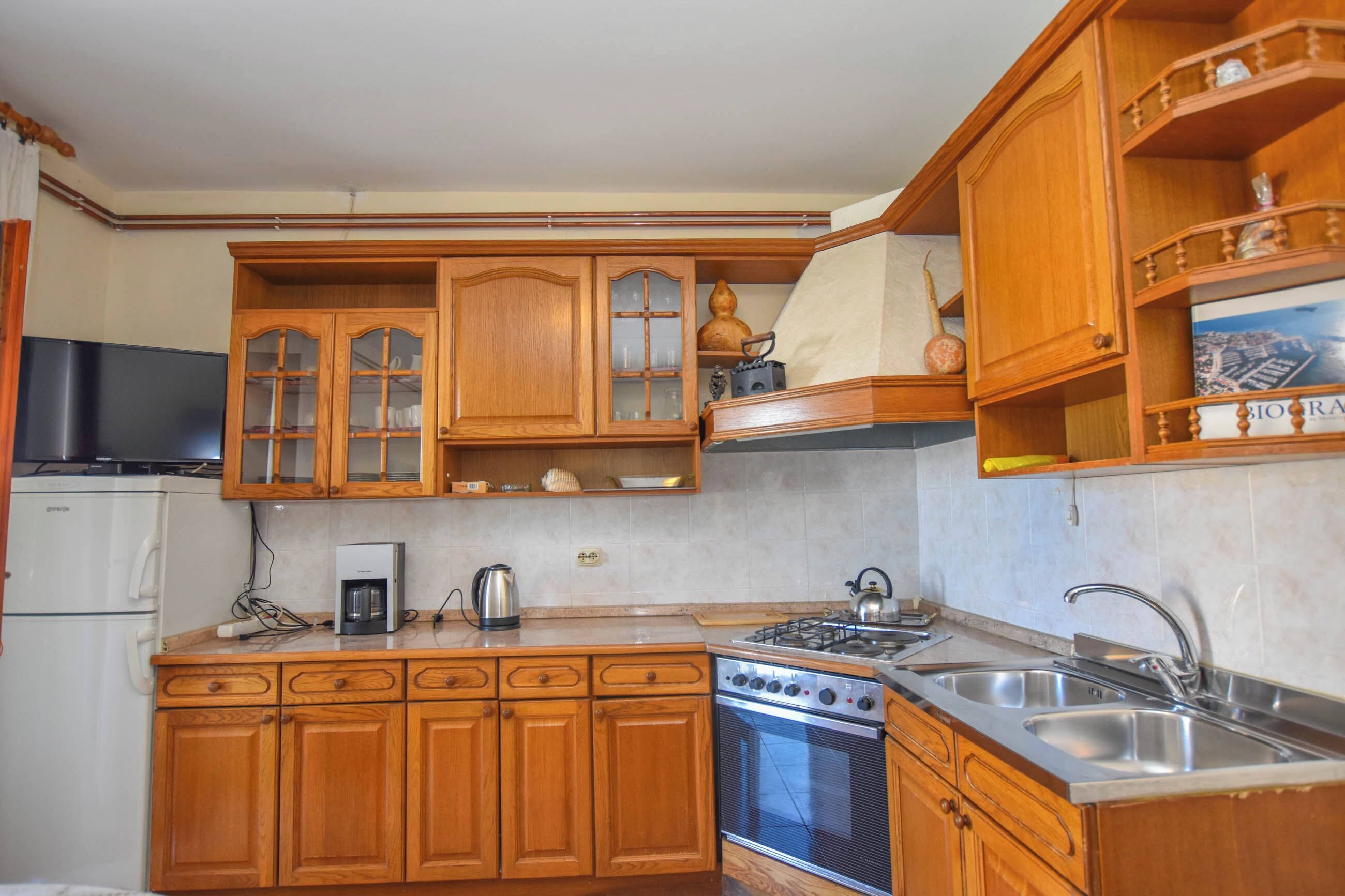 Una cocina con armarios de madera, estufa, fregadero y refrigerador.