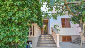A staircase leading to a building entrance, surrounded by lush greenery. - Apartments Immortelle (Biograd na Moru)
