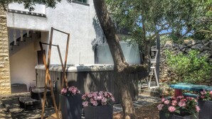 A patio area with outdoor furniture, a tree, and a stone wall. - Apartment Ivana With Jacuzzi (Vir)