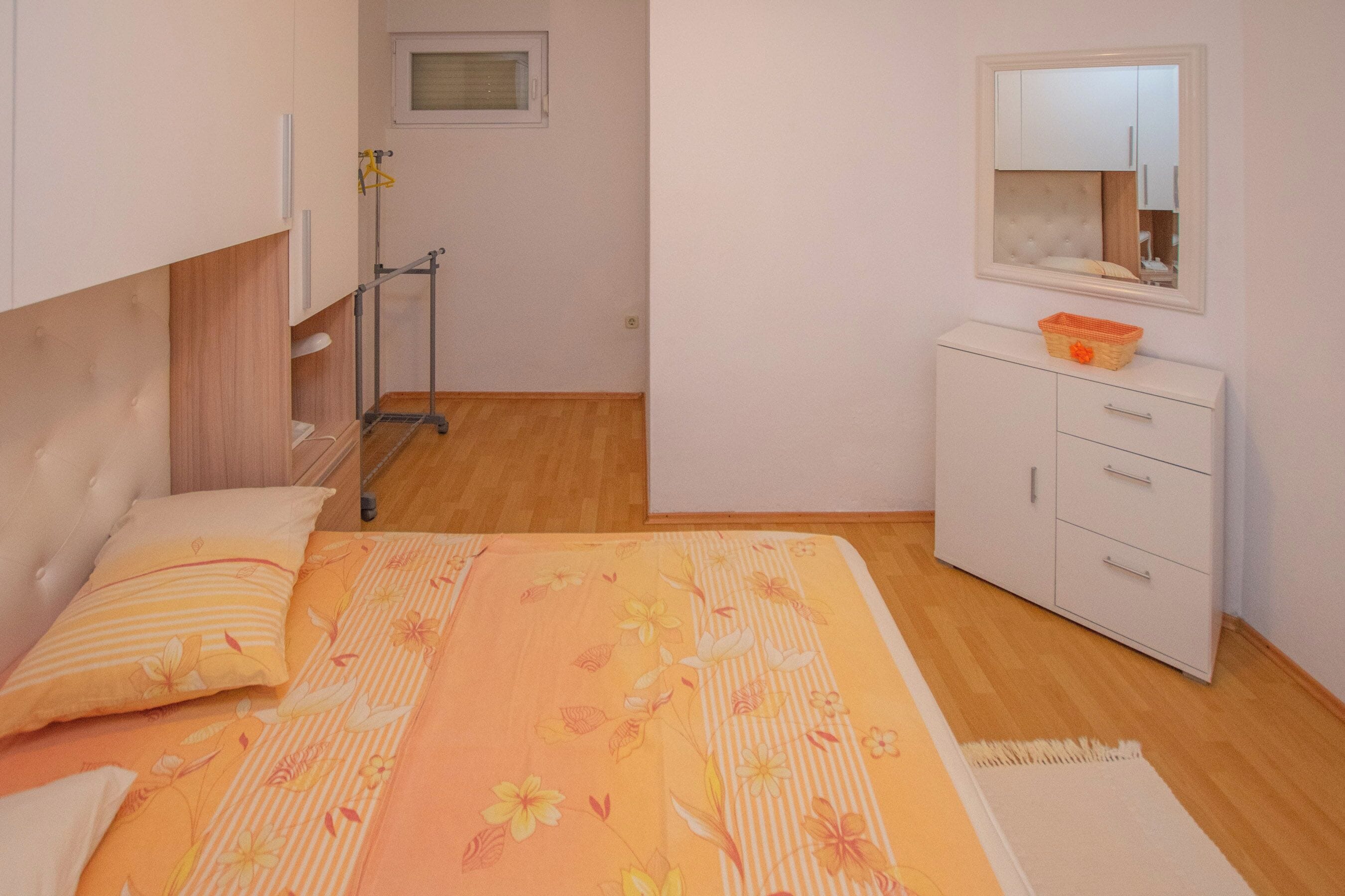 Une chambre à coucher avec un lit, une commode, un miroir et une fenêtre.
