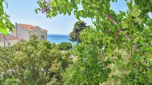 Ein Küstengebäude mit rotem Ziegeldach, umgeben von üppiger Vegetation und freiem Blick auf das Meer.