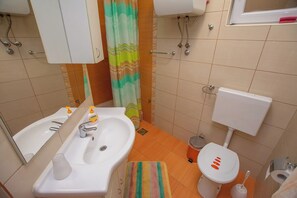 A bathroom with a sink, toilet, and shower curtain. - Apartments Calida A (Pakostane)