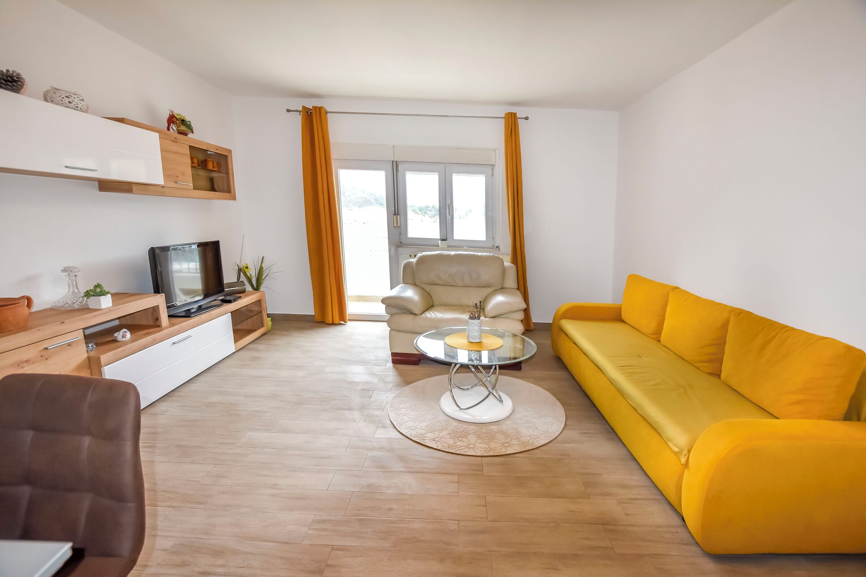 Ein Wohnzimmer mit Sofa, Sessel, Fernseher und Couchtisch.