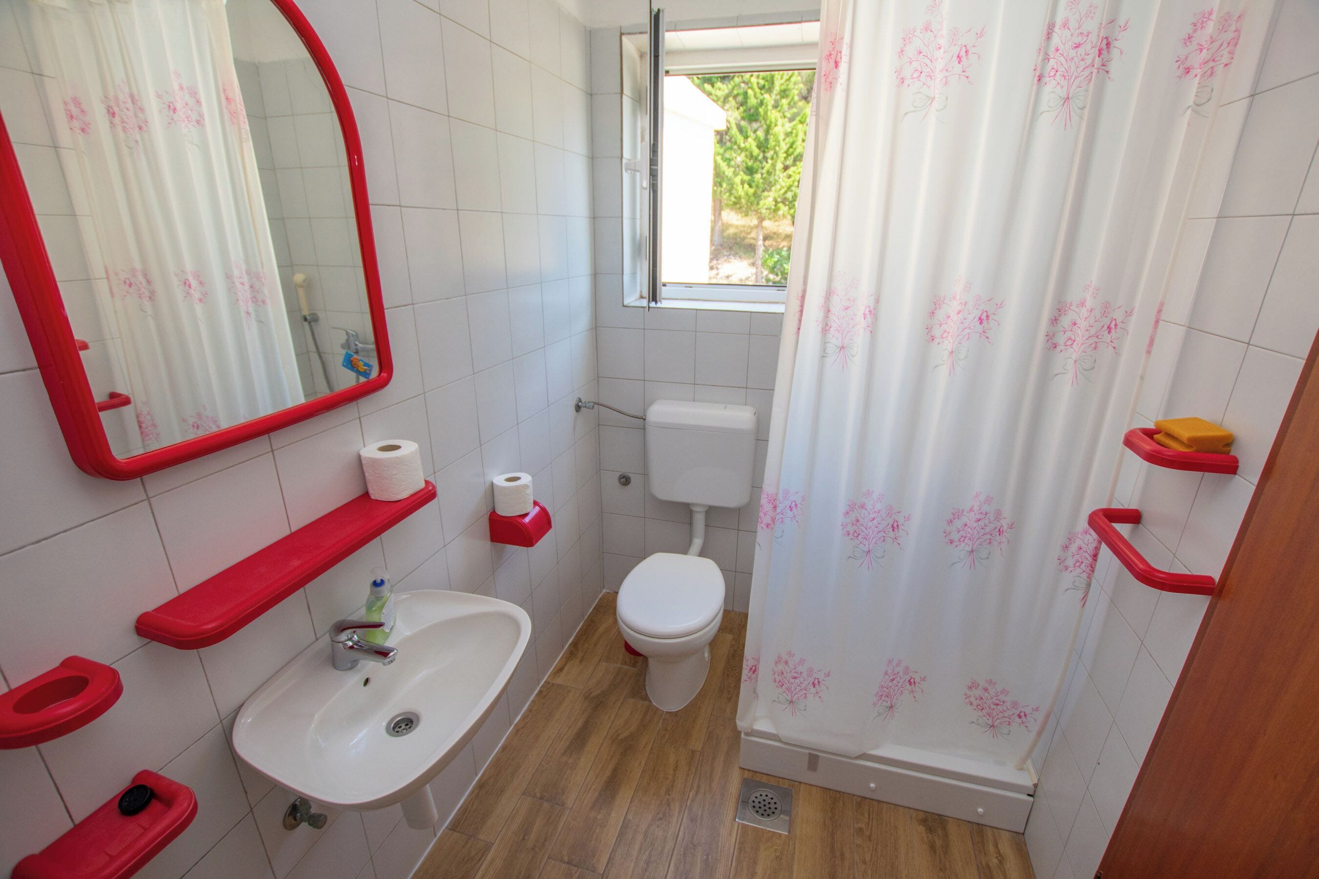 Une salle de bain équipée de toilettes, d’un lavabo, d’un miroir et d’un rideau de douche.