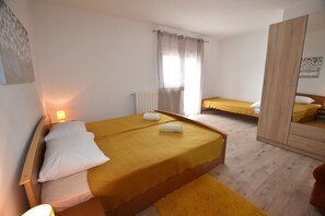 Une chambre avec deux lits, une armoire en bois et un miroir.