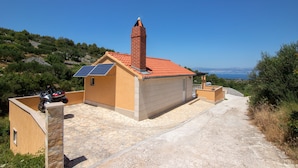 Una piccola casa con tetto in tegole rosse, un camino e un pannello solare sul tetto.
