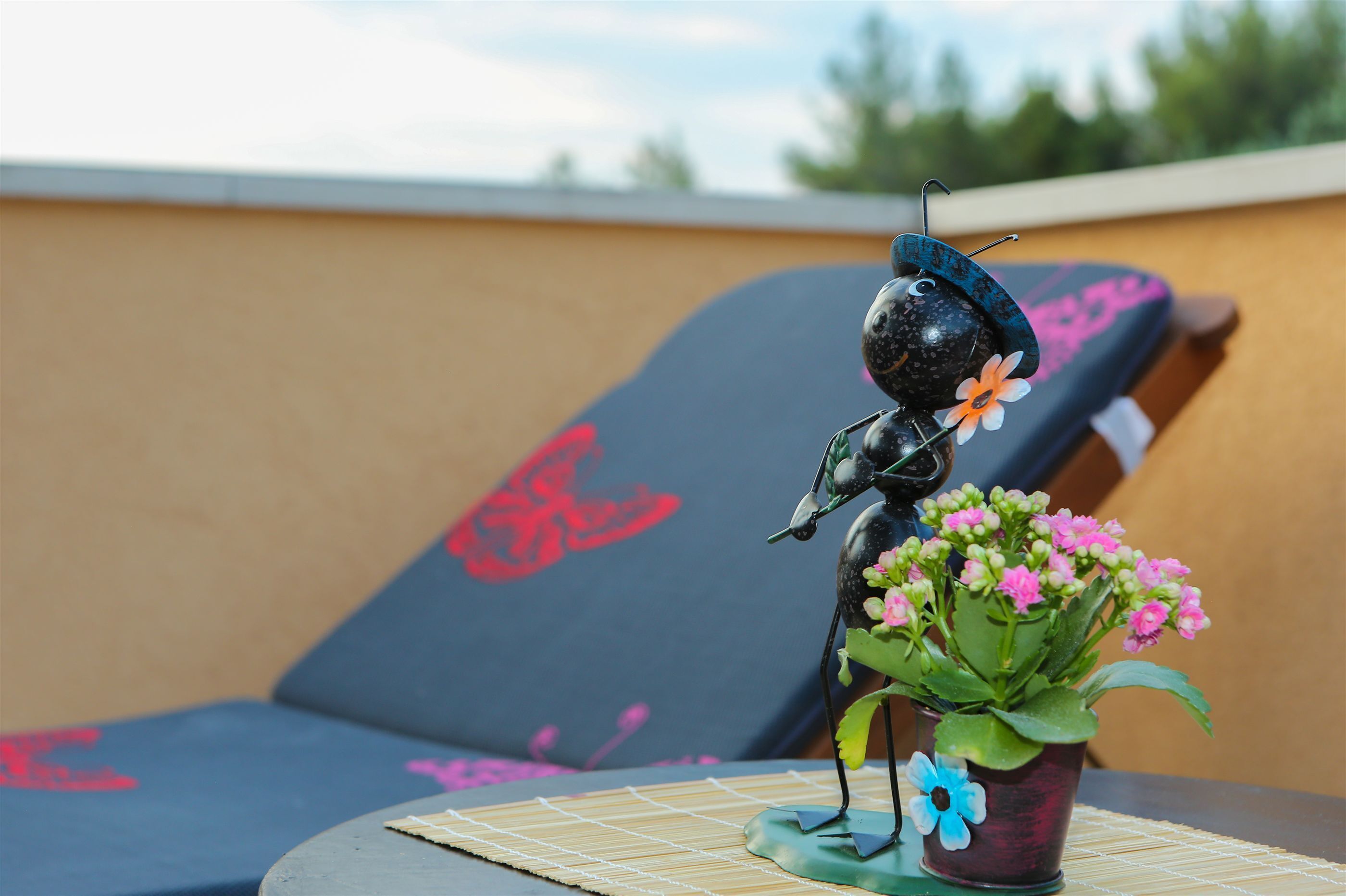 Eine dekorative Metallfigur mit Sombrero und Blumentopf mit Blumen auf einer Tischplatte.