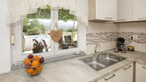 Eine Küche mit Fenster, Spüle, Kaffeemaschine und Obstkorb.