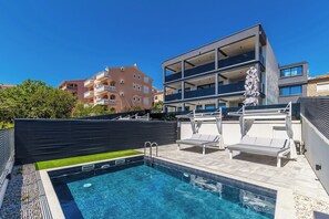 A rooftop swimming pool with a modern design, surrounded by a black fence and a small grassy area. - Villa Three Units (Crikvenica)