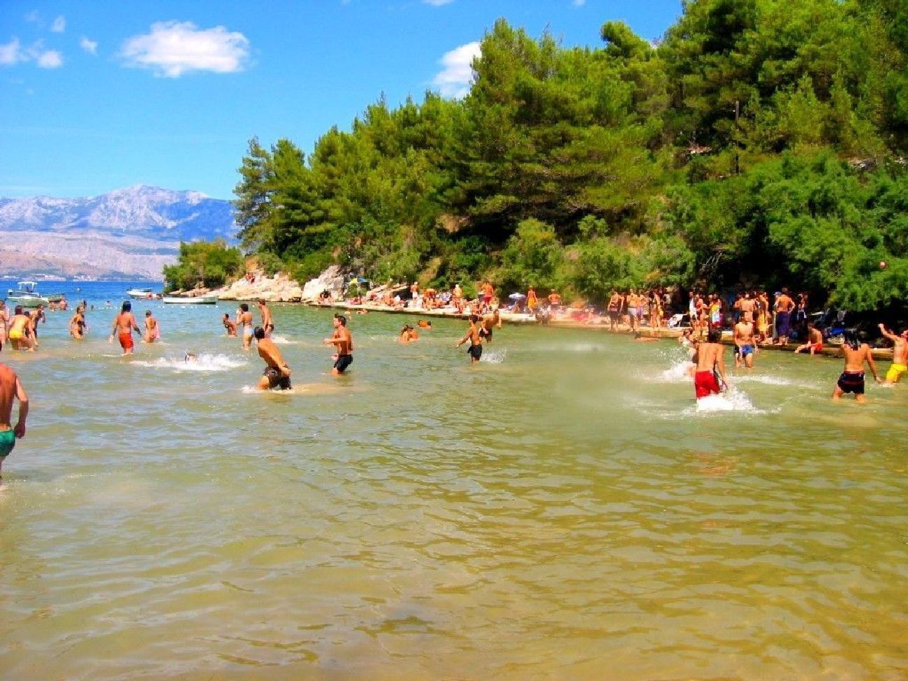 Ein überfüllter Strand, Menschen baden und genießen das Wasser.
